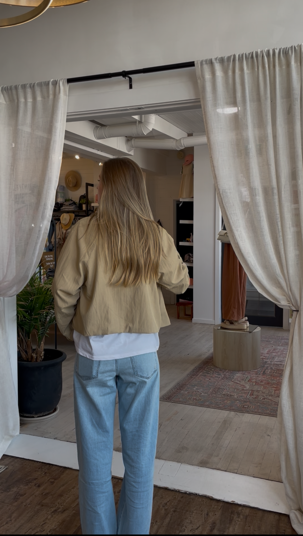 Person standing in a room with curtains and a rug