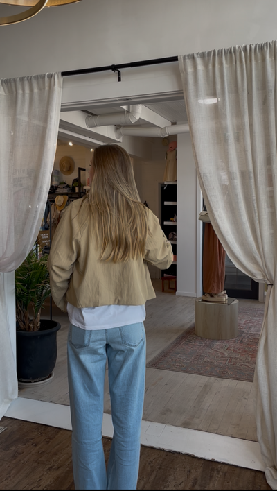 Person standing in a room with curtains and a rug